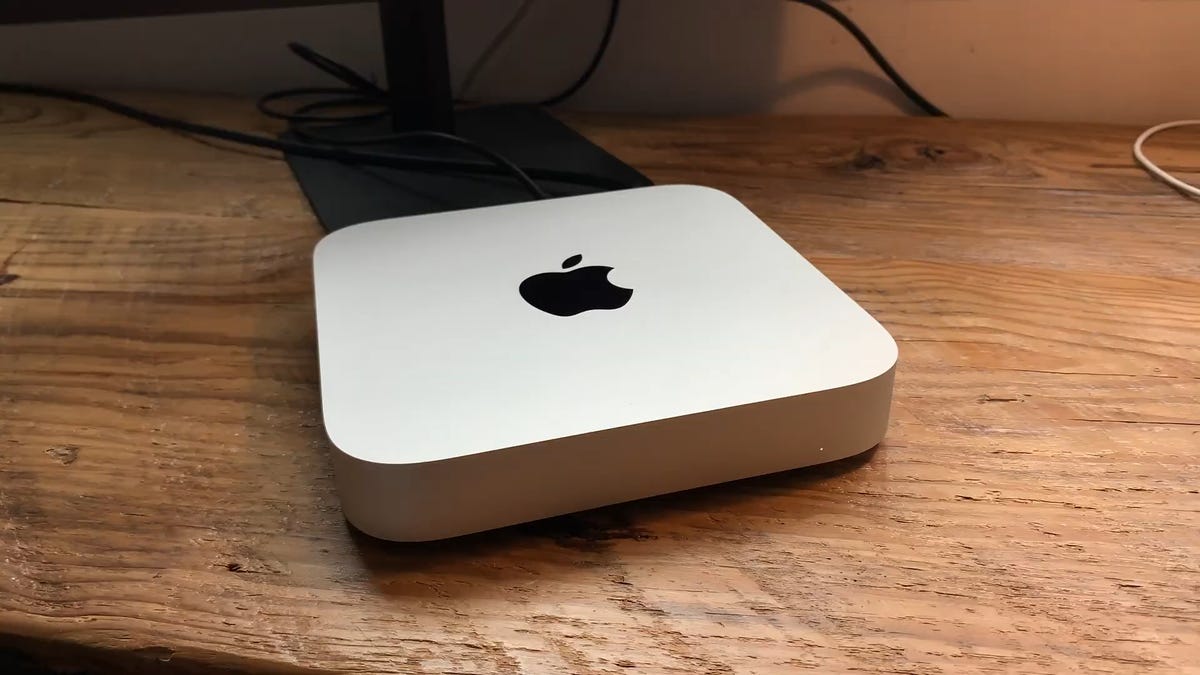 Close up of a silver Mac mini on a wooden desktop.