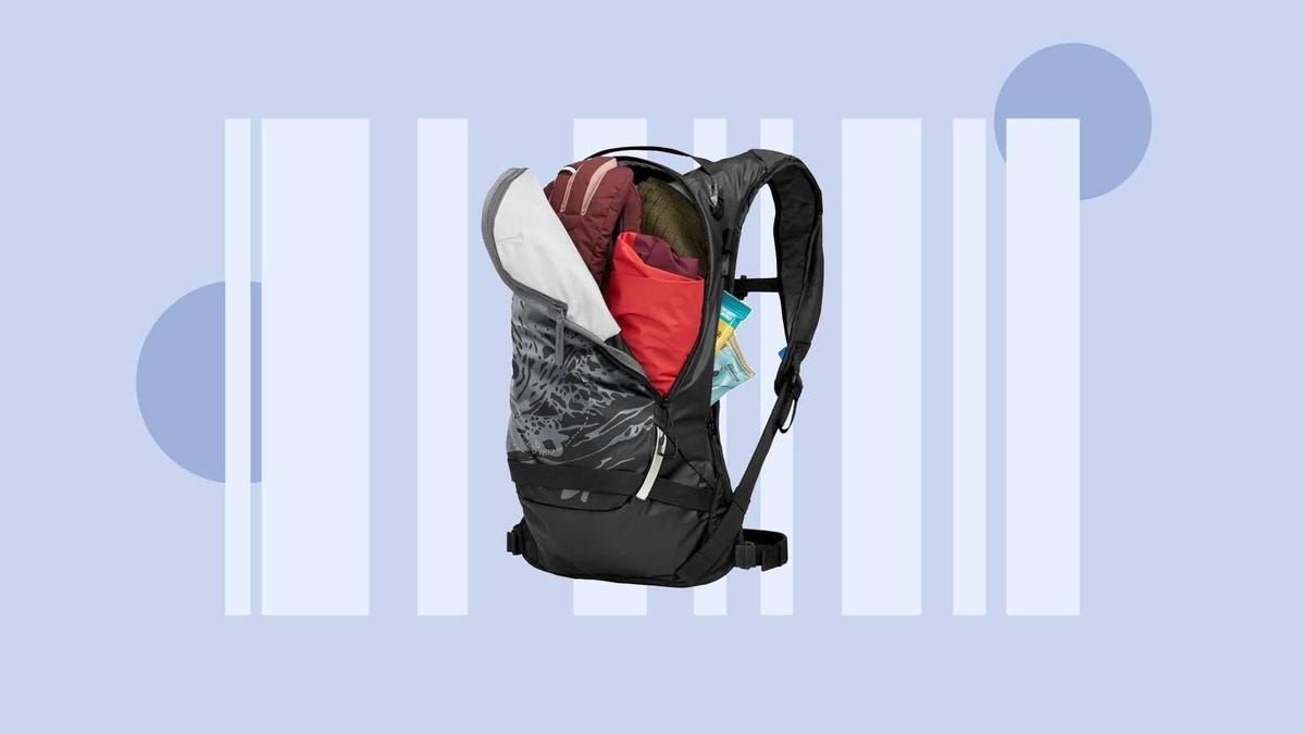 An open CamelBack hydration backpack with clothes inside against a gray/blue background.