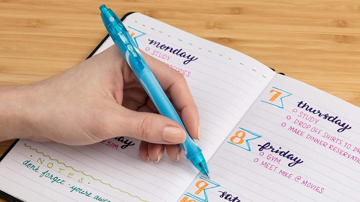 A hand writing in a notebook with a blue pen.