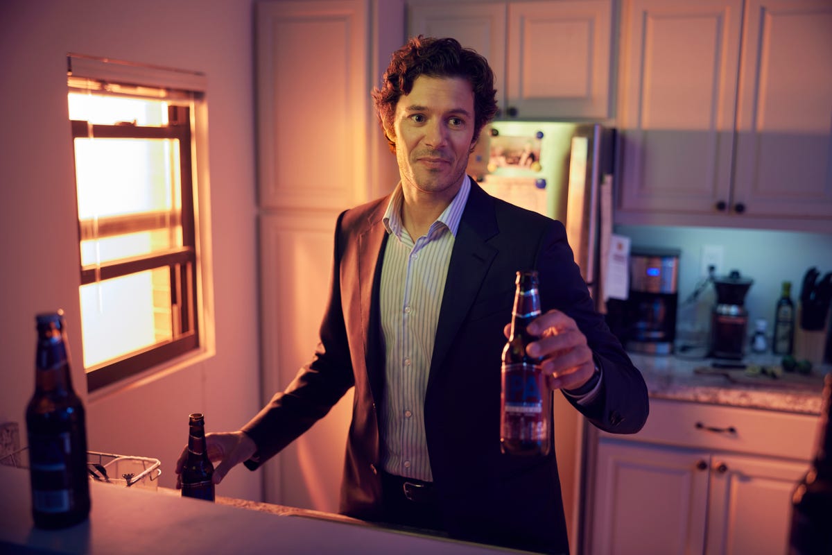 Adam Brody as Seth, offering a bottle of beer.