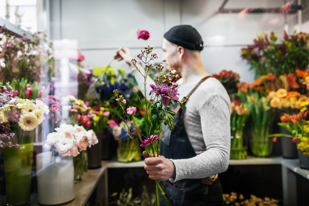 A florist taking care of various flowers and bouquets in his shop.
