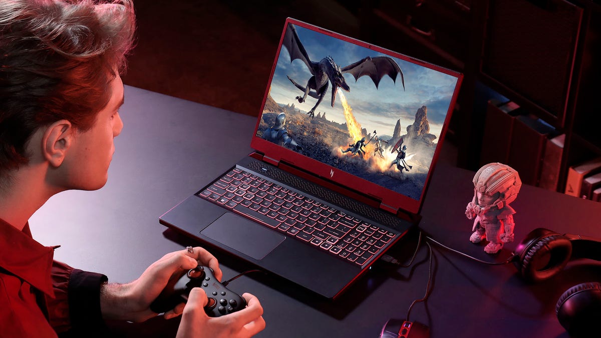 Acer Nitro 16 gaming laptop on a desk with a man playing a game using a controller.