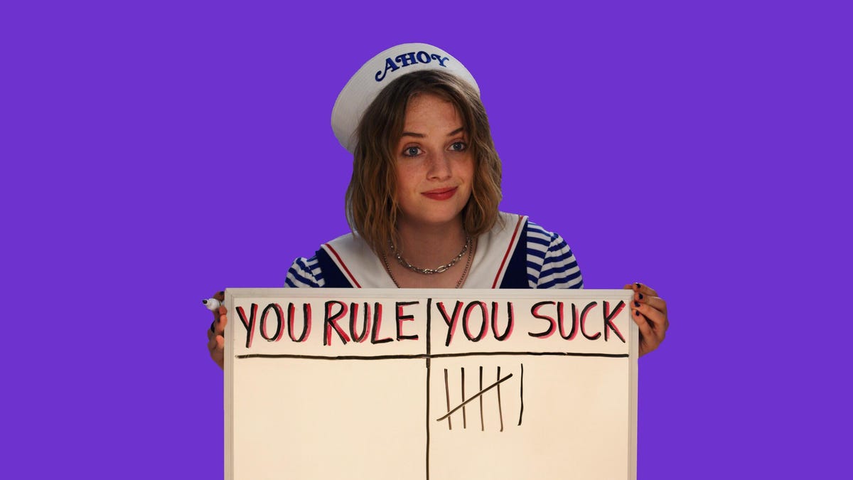 Stranger Things character Robin holds a white board with "You Rule" and "You Suck" written on it, with six tick marks in the "You Suck" column (and zero under "You Rule.").