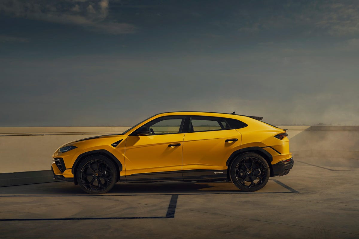 An Urus Performante moodily lit in a studio, with bigger wings, fenders, wheels and tires than a regular Urus.