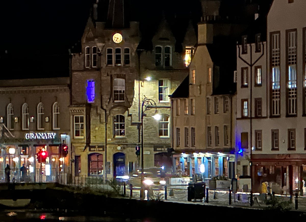 A row of buildings along a river at night cropped in