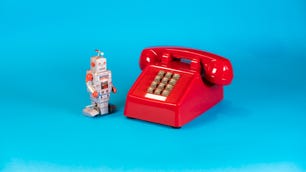 A vintage robot next to a red telephone