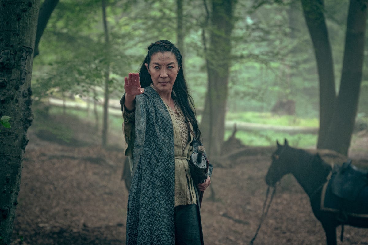 Michelle Yeoh as a Scian with a sword at her hip and palm outstretched forward