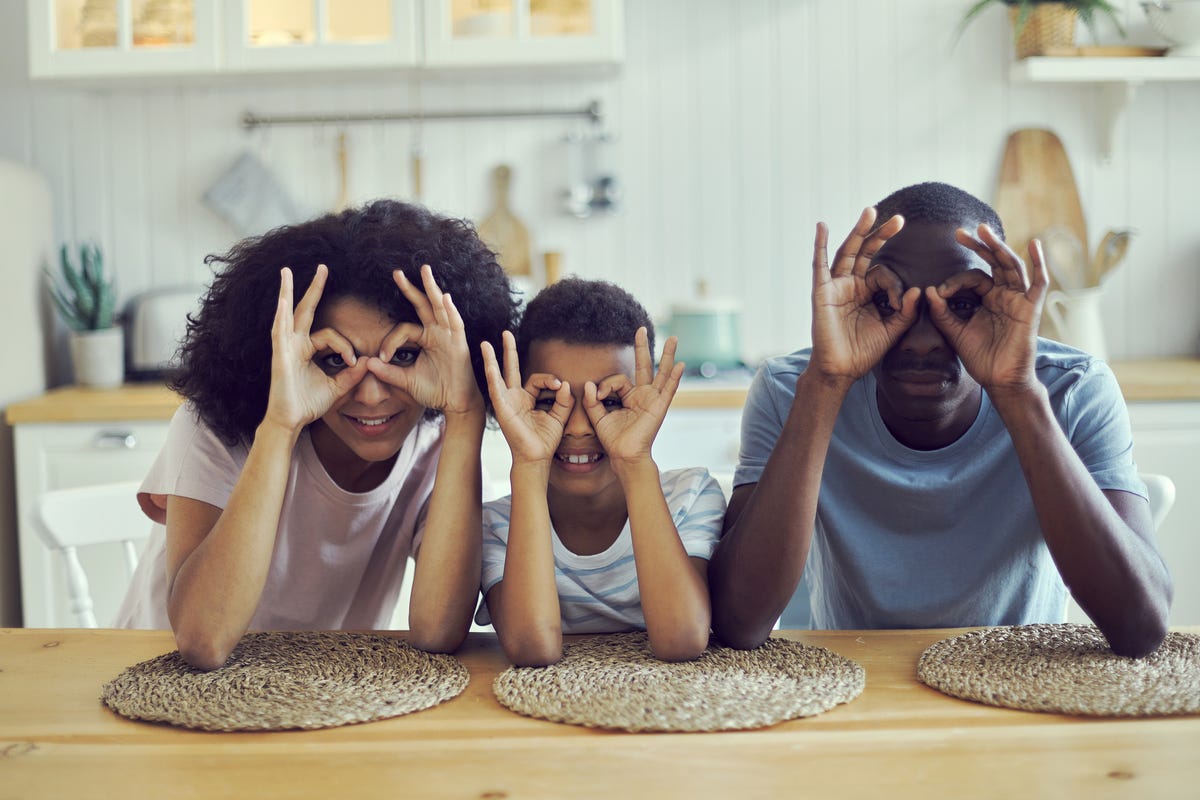 Two parents and their son make glasses are making glasses with their hands