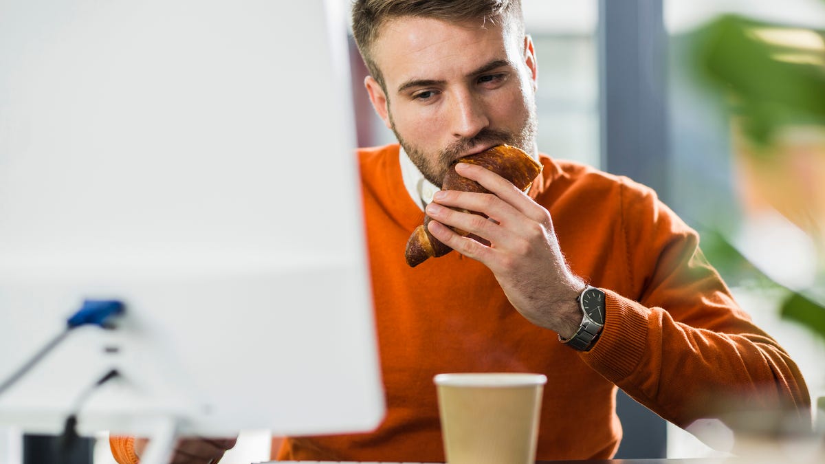 Man eating a snack while stressed at work.