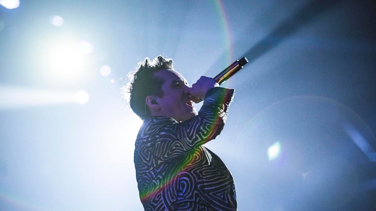 American singer Brendon Urie of Panic! At The Disco is dramatically silhouetted by a stage light as he sings.