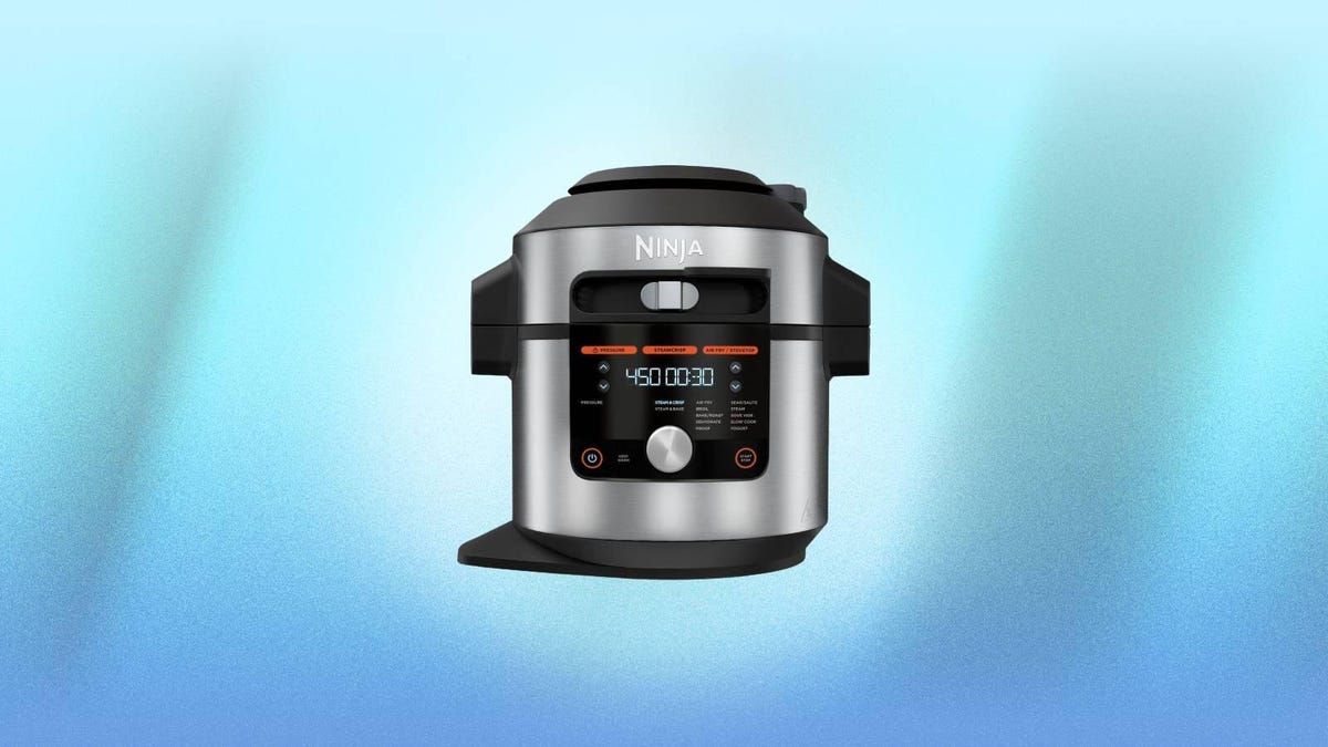 A stainless steel Ninja multicooker against a blue background.