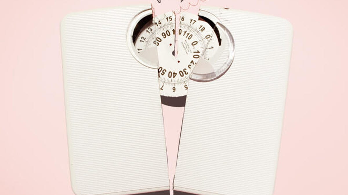 A white scale is smashed in half on a pink background.
