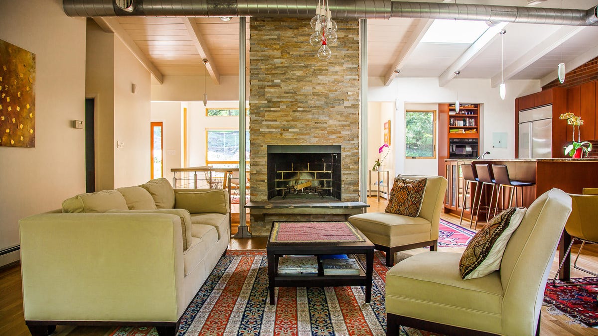 living room with beige couches, a striped rug and a central chimney