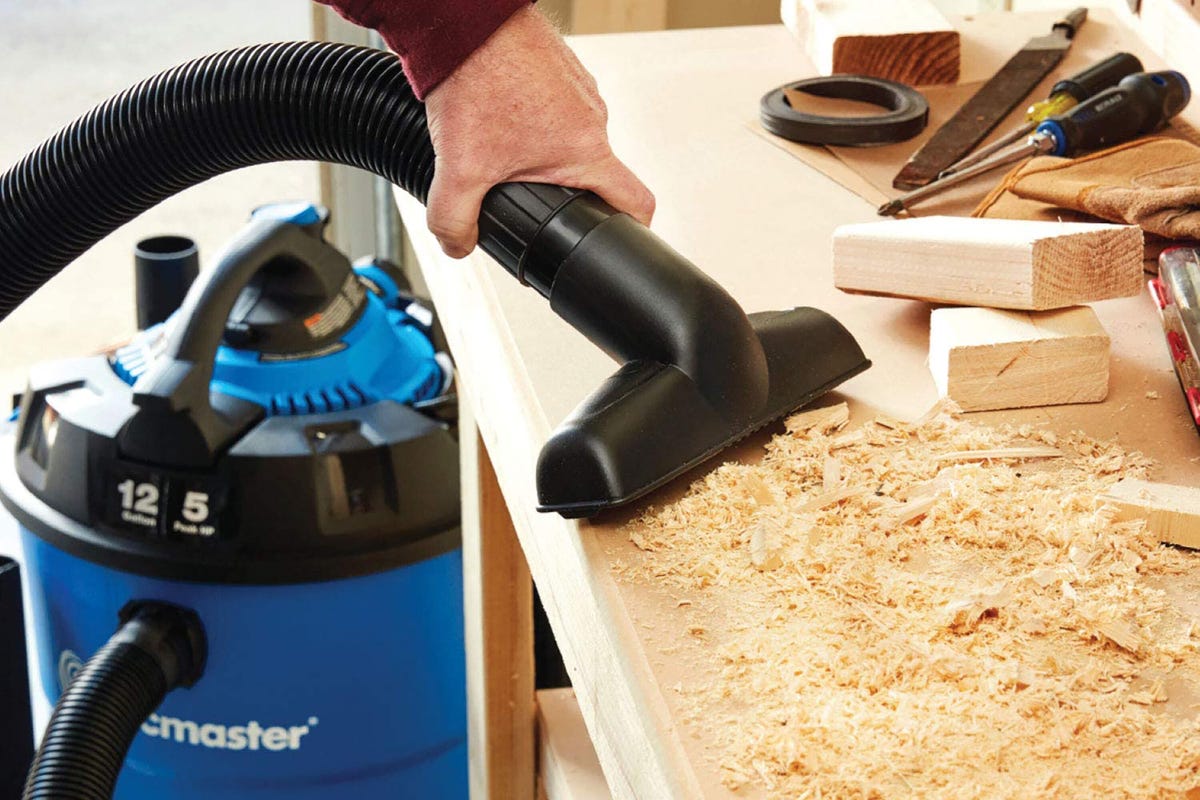 A shop vac being used to clean up sawdust. 