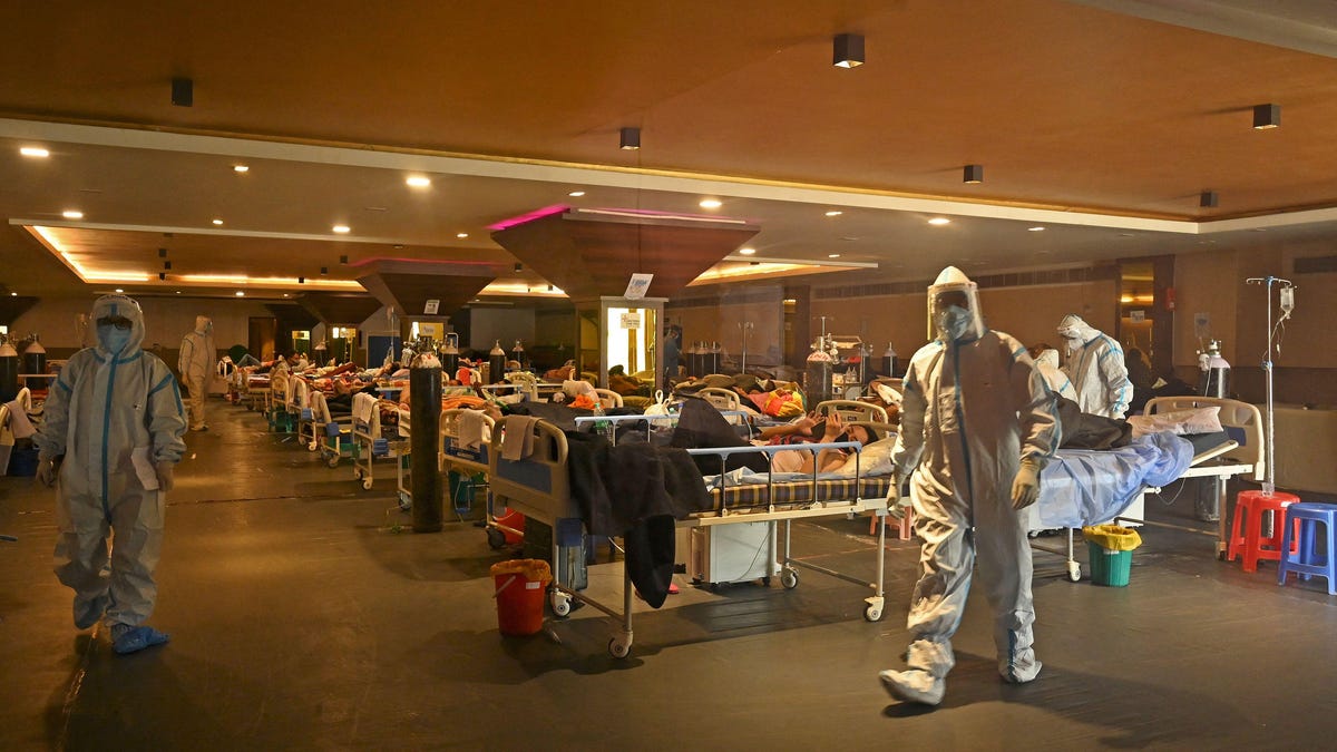 COVID care center in New Delhi with patients in beds and health care workers in PPE