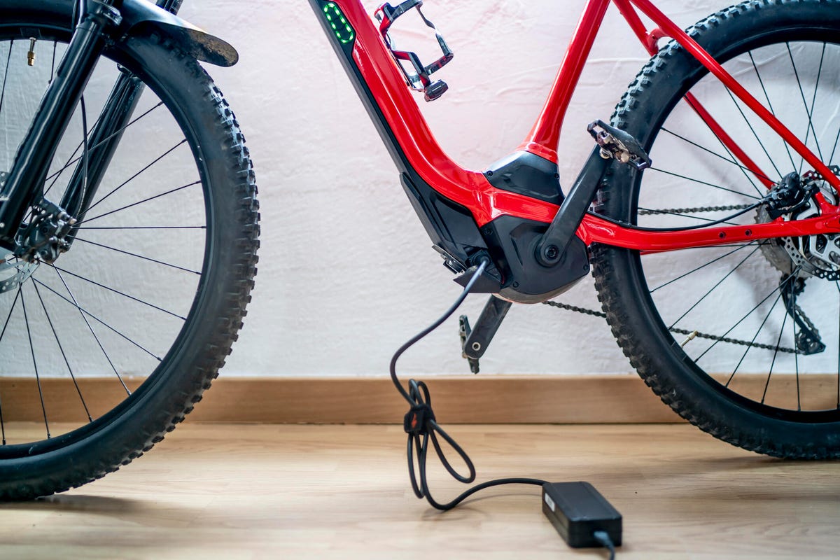 Close-up of the frame of a red e-bike connected to a charger