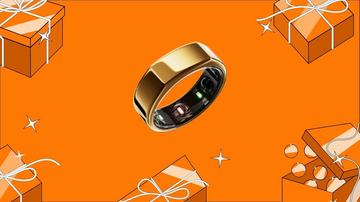 A gold Oura smart ring against an orange background surrounded by presents.