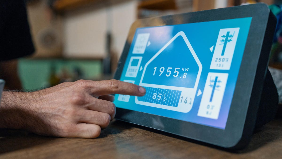 A person taps a tablet screen displaying home energy information.
