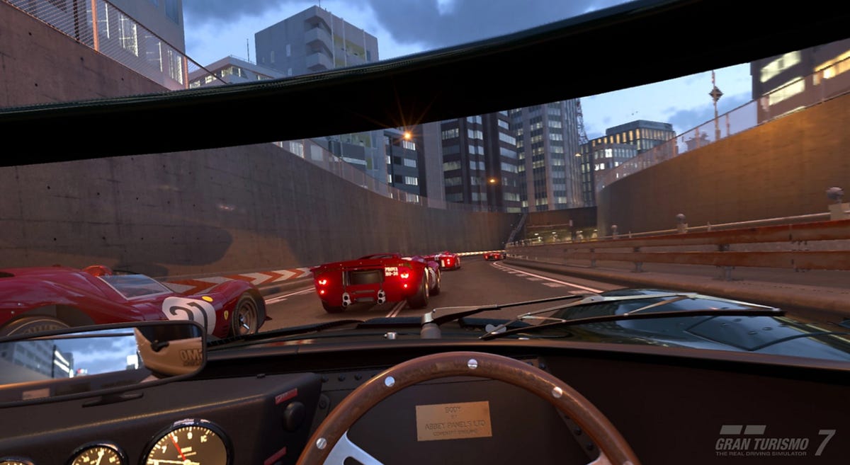A cockpit view of racing on a highway in the video game Gran Turismo 7