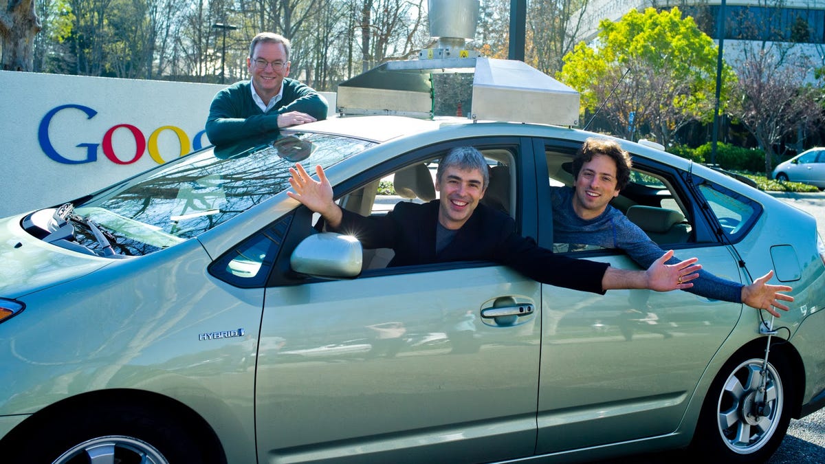 Google co-founders Larry Page, left, and Sergey Brin, inside a Google self-driving car, with Executive Chairman Eric Schmidt standing behind. The self-driving cars are reportedly part of Google X, a collection of advanced technology projects.