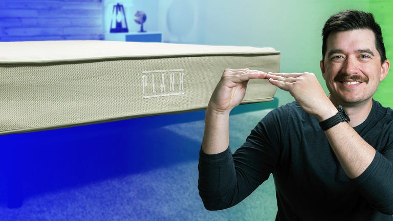The Plank Firm Natural mattress against a colorful background with a man smiling in the front.
