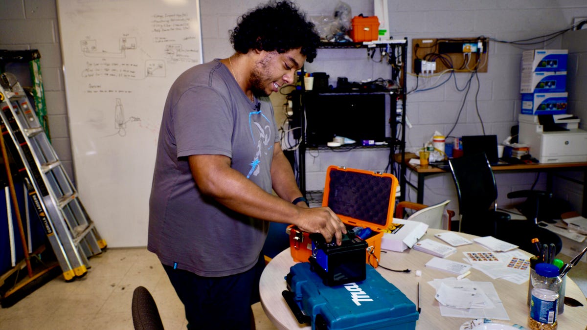 NYC Mesh volunteer in mesy workroom shows fiber splicing equipment