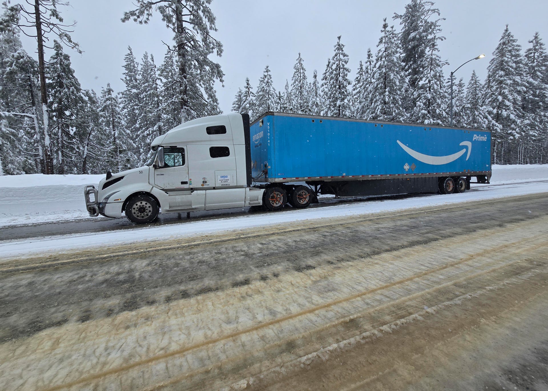An Amazon truck stops to put on snow chains, as the driver prepares for Interstate 80 to reopen to trucks after being closed for three days.