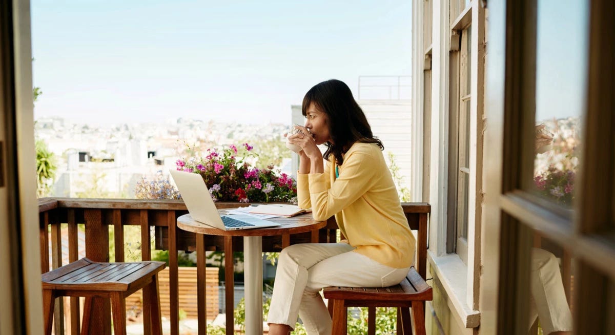 woman using a laptop on a porch.