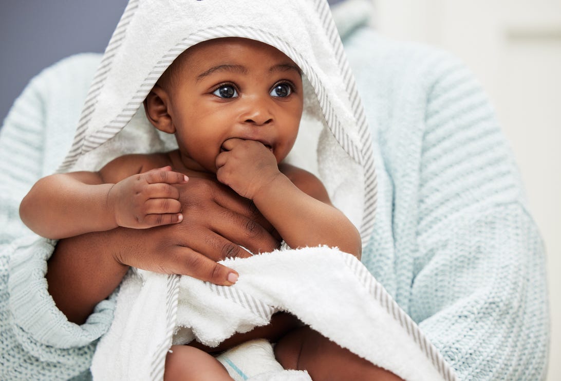 baby wrapped in a towel being held by a parent