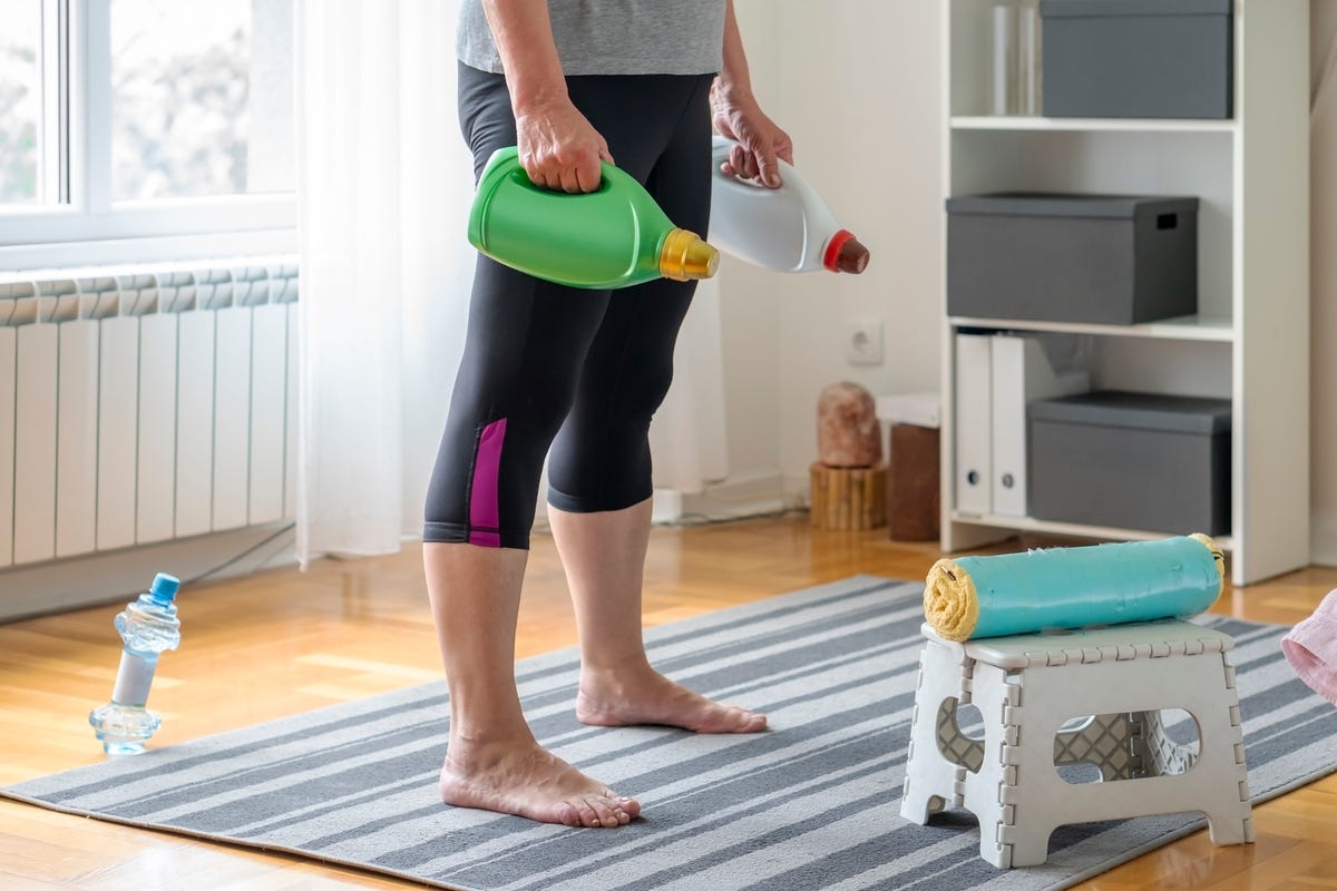Una mujer hace ejercicio en casa con detergente para ropa.