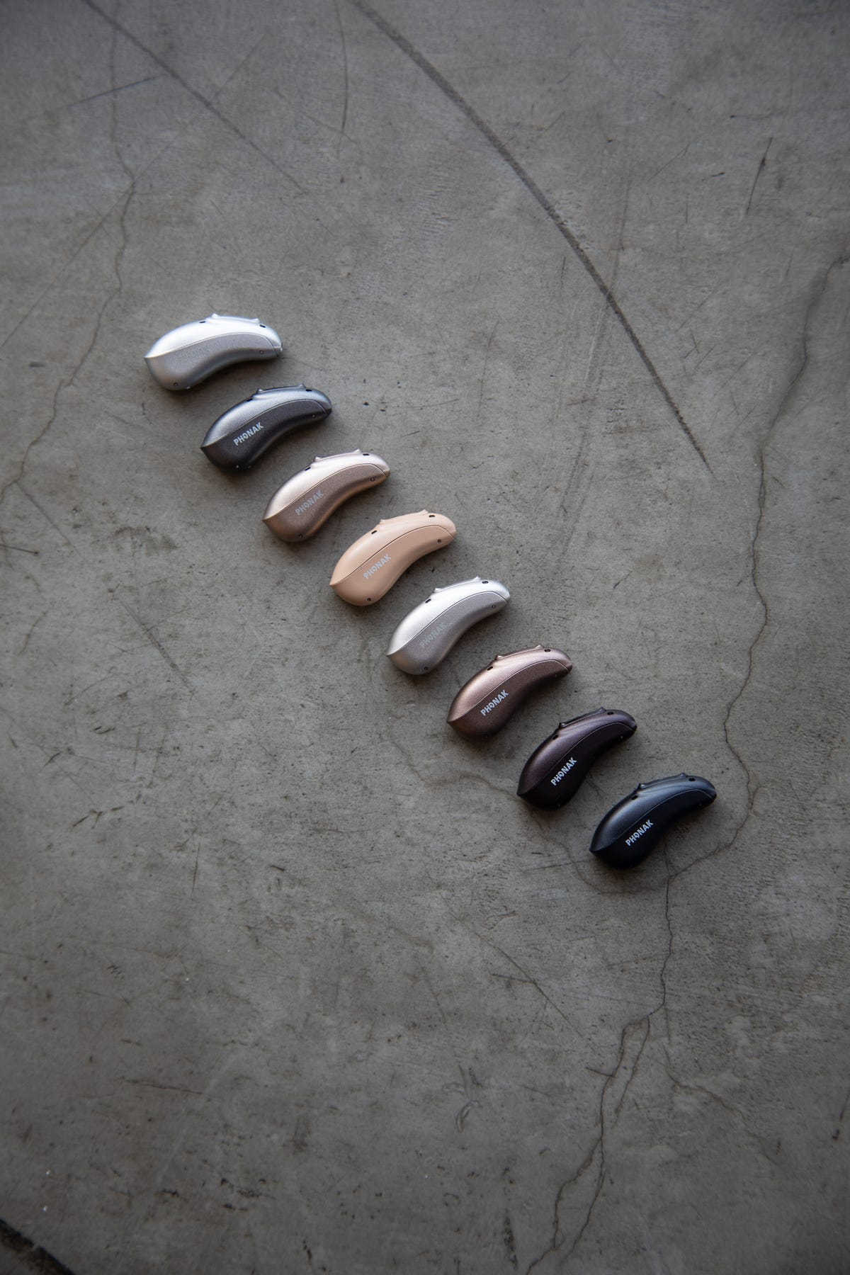 A handful of hearing aids in different colors lined up 