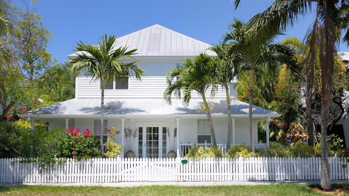 A white two story house in Florida with a white picket fence.