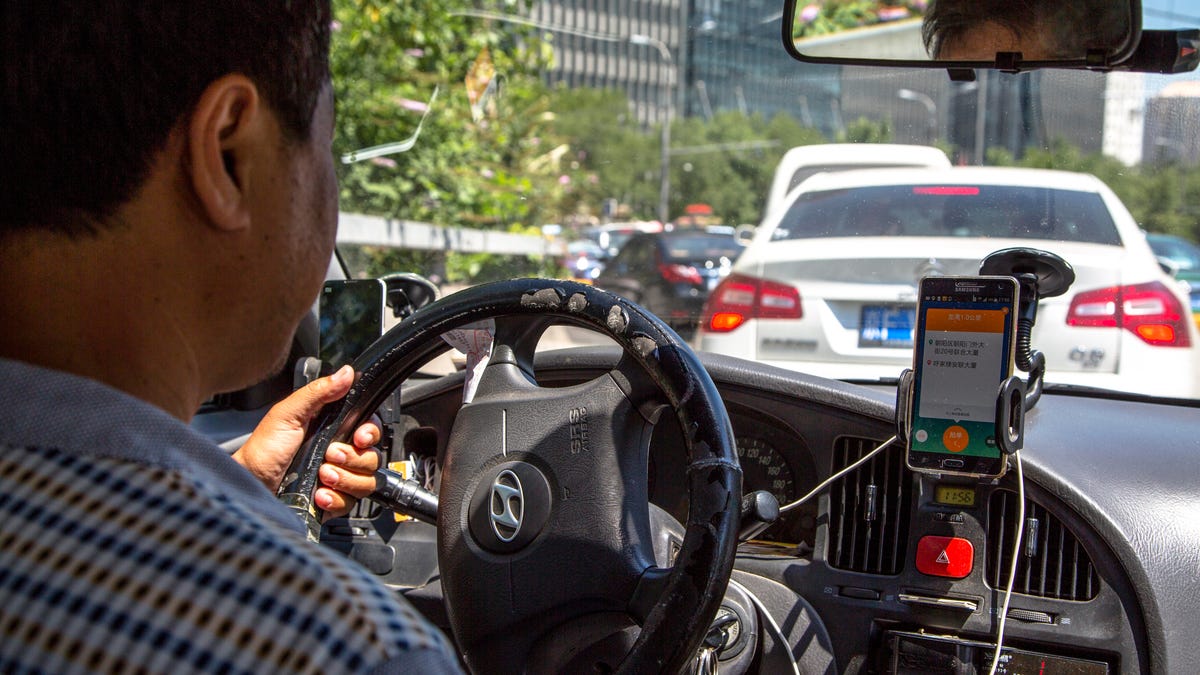 A taxi driver is using Didi Dacha App while driving on the