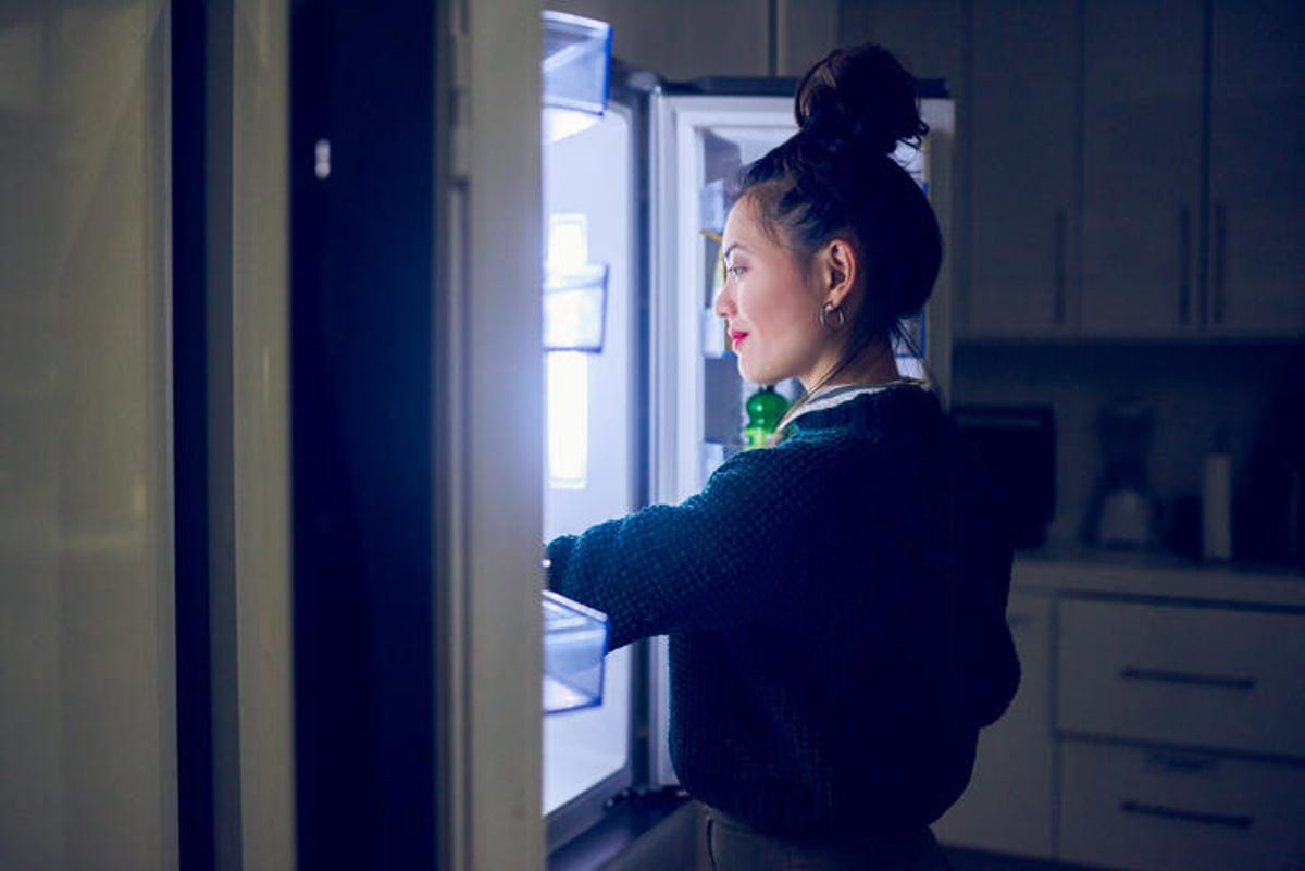 A woman looking for food in the refrigerator at night