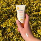 Hand holding Aveeno protect and hydrate sunscreen