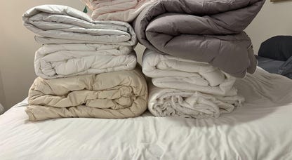 Seven comforters on a bed for testing.