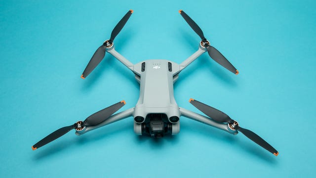 DJI Mini 3 Pro drone with rotors folded out on a blue background.