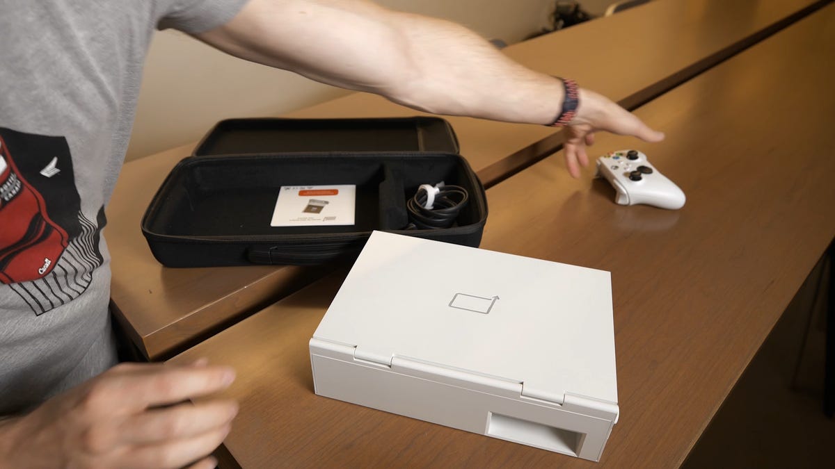 The xScreen in the foreground with the opened accessory case in the background showing the author reaching for the controller to put in the case
