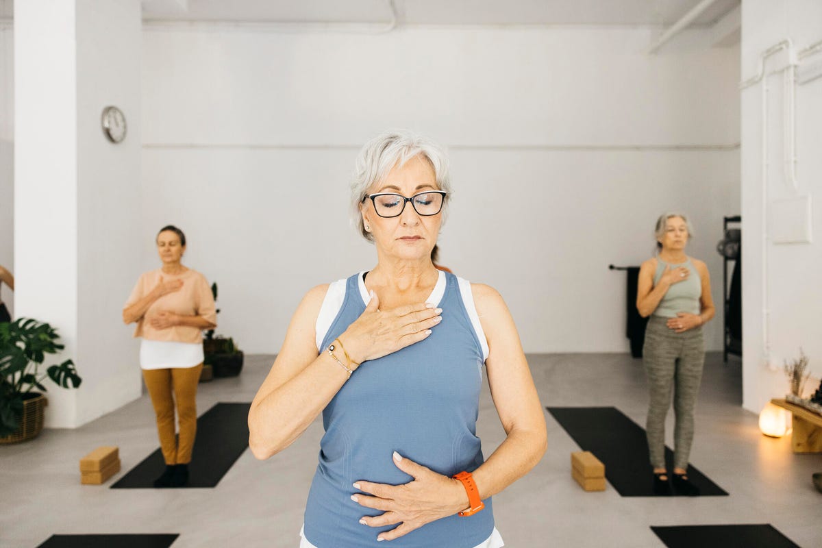 Mujer con los ojos cerrados mientras respira en un estudio de yoga.