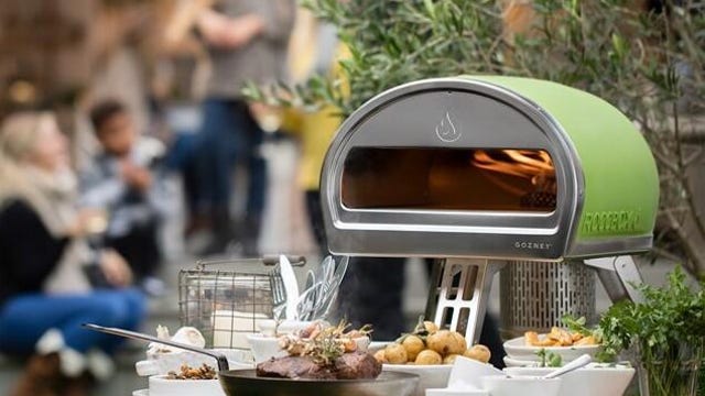 green pizza oven sitting on outdoor table