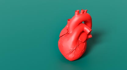 A red plastic heart against a green background