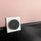 Una pequeña cámara web blanca sobre un fondo rosa