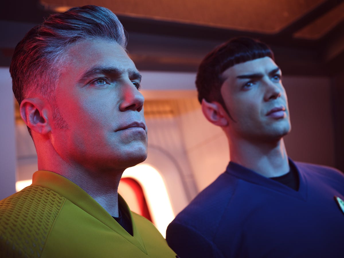 Captain Pike and sexy young Spock look ahead in atmospheric lighting on the bridge of the Enterprise in Strange New Worlds.