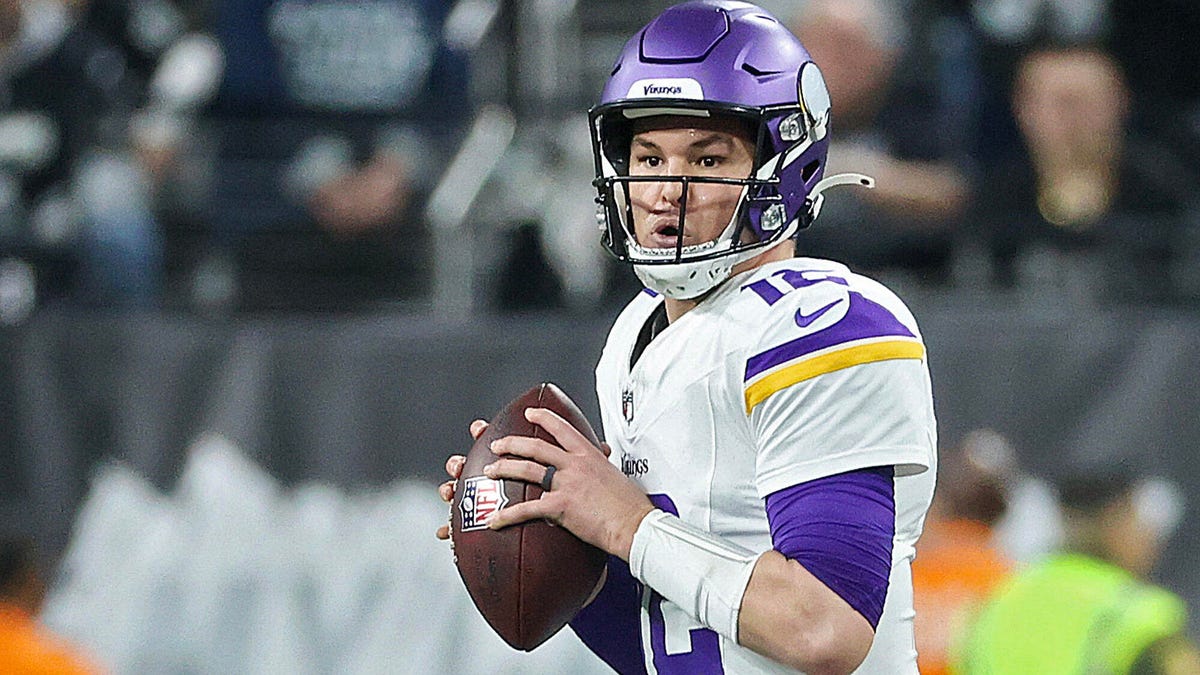 Nick Mullens of the Minnesota Vikings clutching the ball with both hands as his prepares to throw.