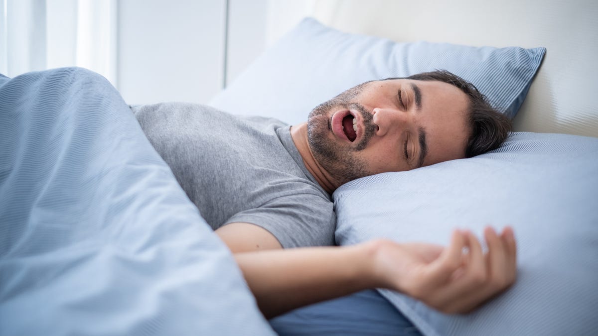 Man snoring while sleeping on bed.