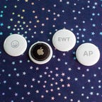 four round apple airtags with different engravings, including the initials AP and a happy face emoji