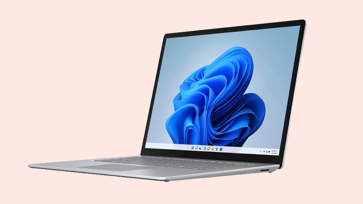 An open Microsoft Surface Laptop against a light orange background. 