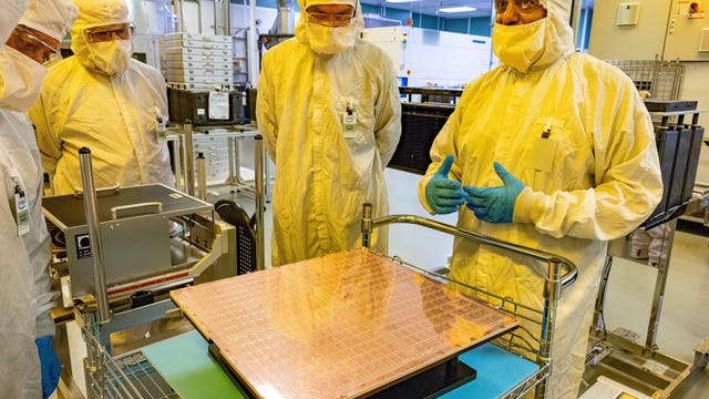Rahul Manepalli, right, Intel's module engineering leader, shows a glass substrate panel before it's sliced into the small rectangles that will be bonded to the undersides of hundreds of test processors. The technology, shown here at Intel's CH8 facility in Chandler, Arizona, stands to improve performance and power consumption of advanced processors arriving later this decade. Glass substrates should permit physically larger processors comprised of several small 