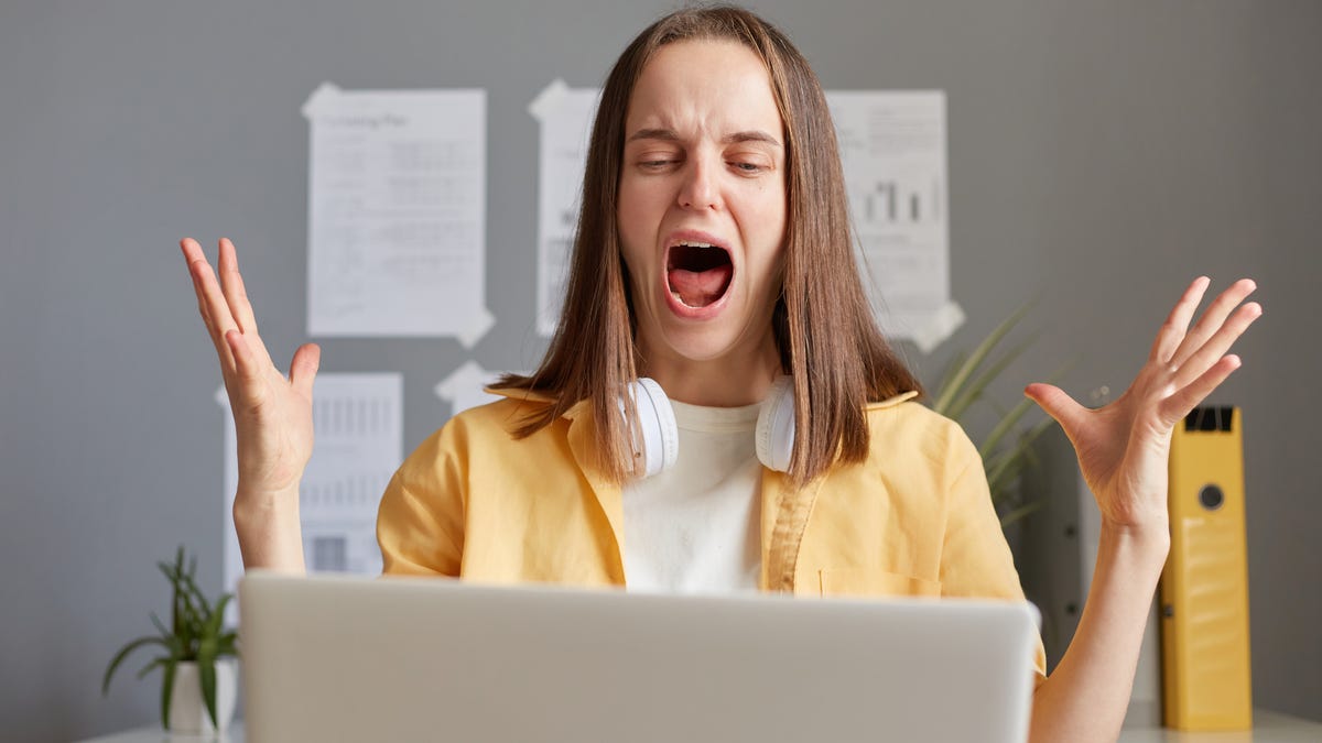 Woman screaming in front of her computer, clearly frustrated