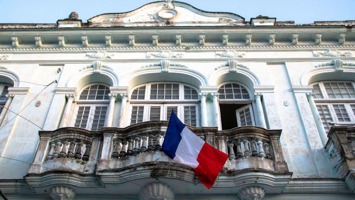 French flag hanging on an old house balcony during the